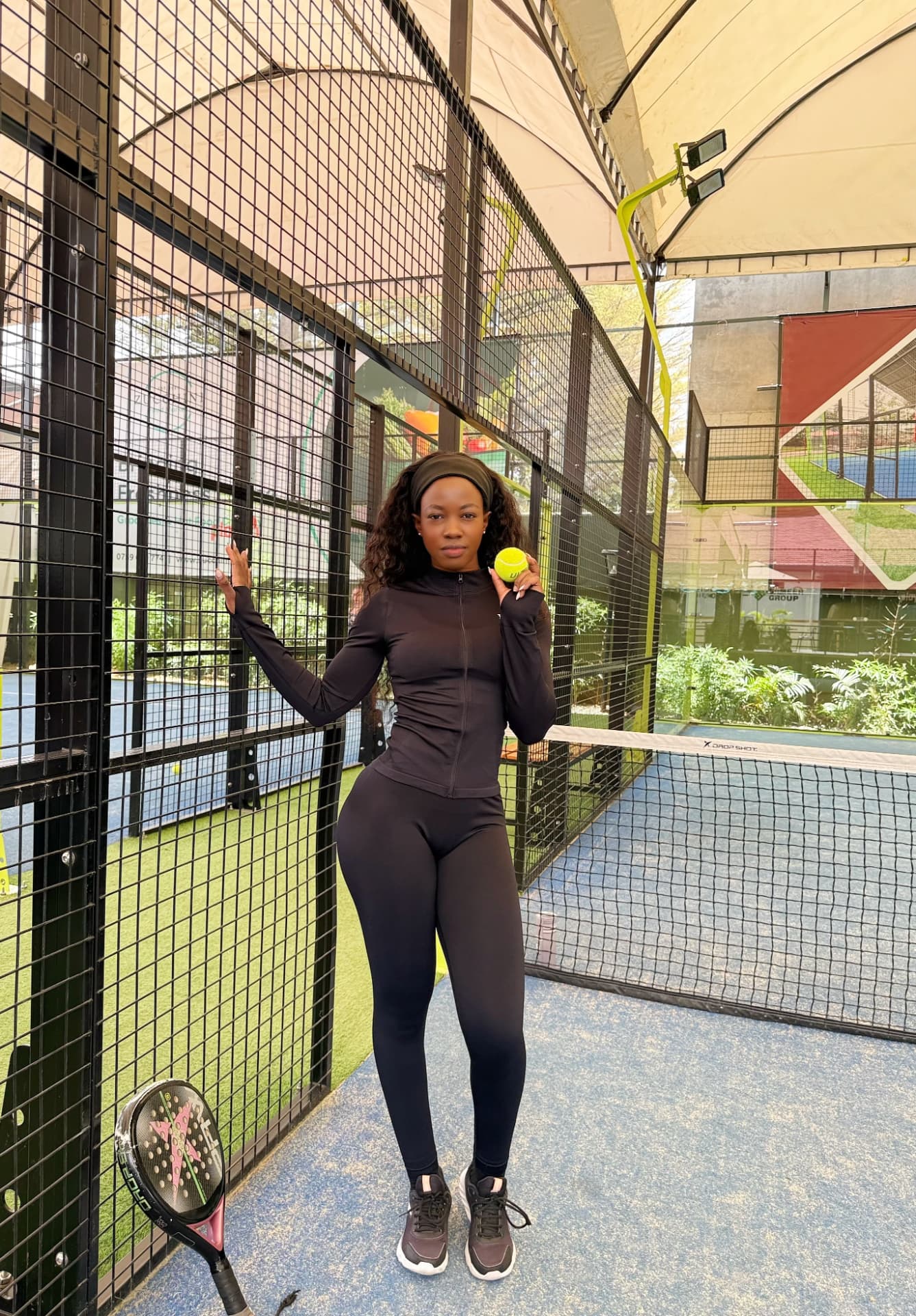 Woman in a black Valentin Noble training set on a padel court