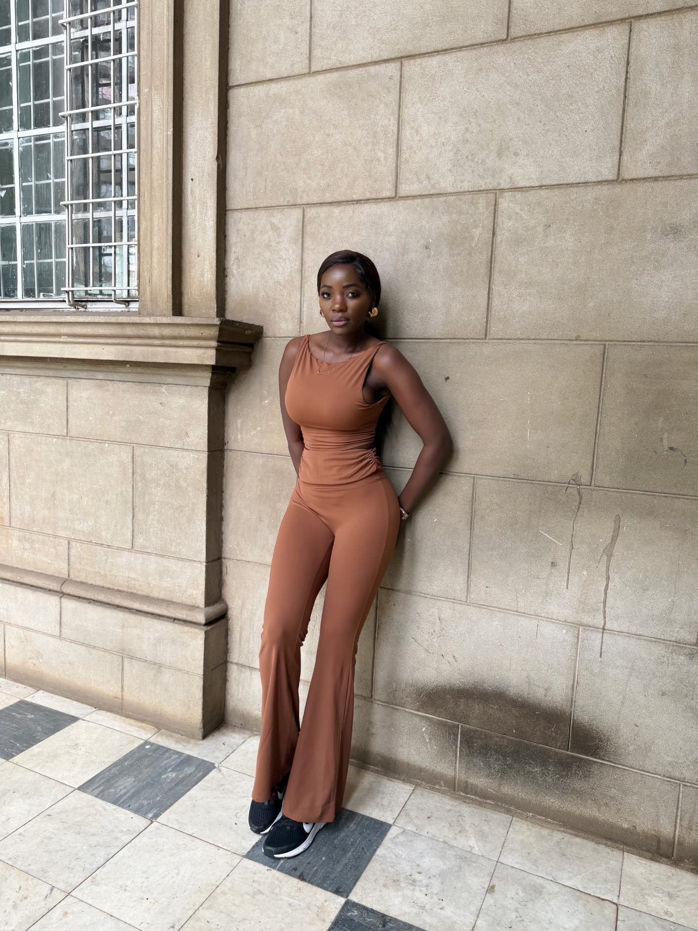 Woman wearing a mocha sleeveless top and flared trousers